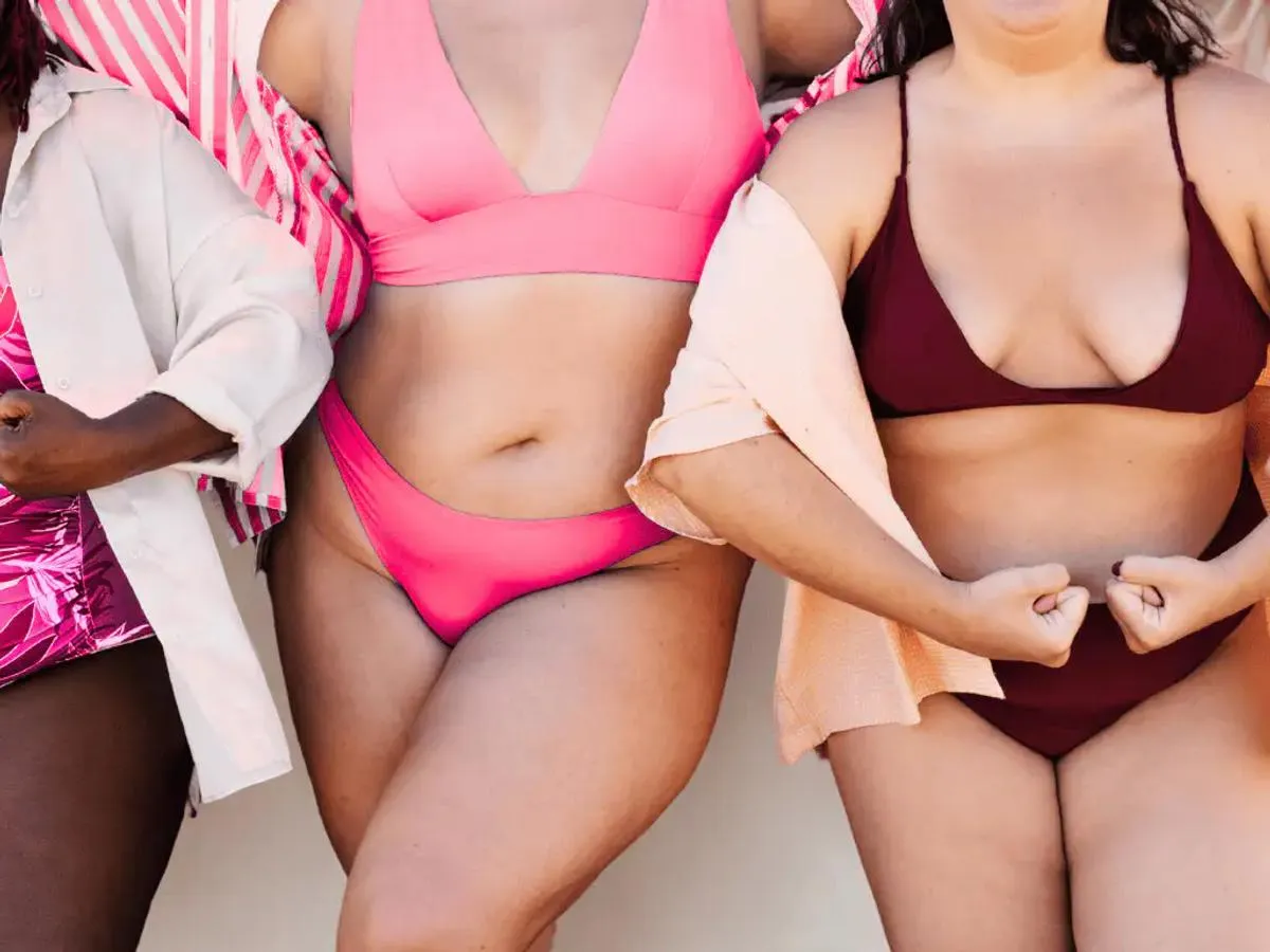 Mehrere Frauen mit Lipödem stehen nebeneinander und tragen unterschiedlich farbige Bikinis und leichte Strandkleidung; das Bild zeigt verschiedene Körperformen 