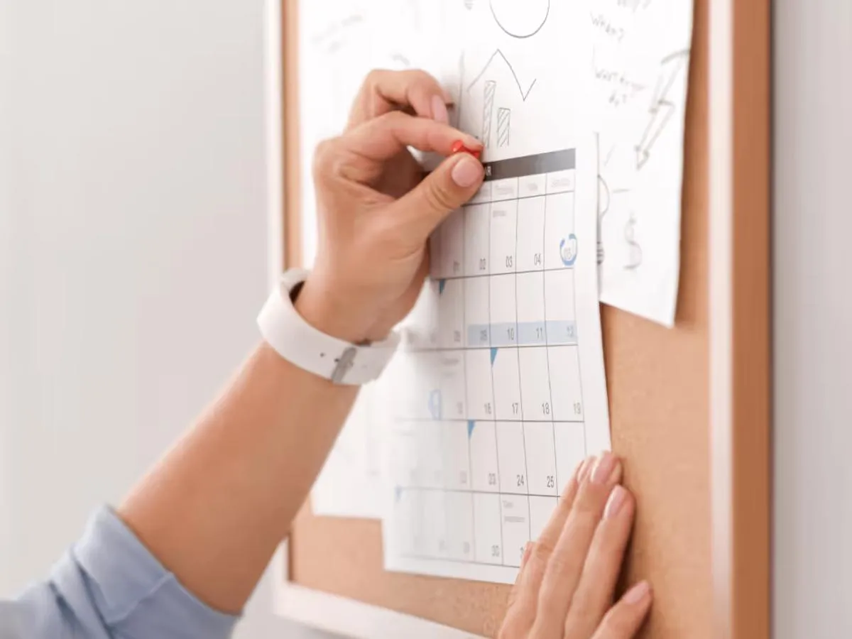 Frau hakt am Wandkalender ihre Routinen ab